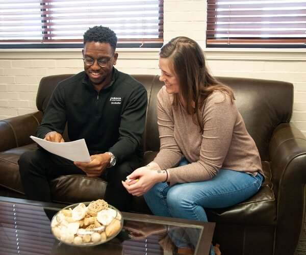 two employees sitting on couch going over paper