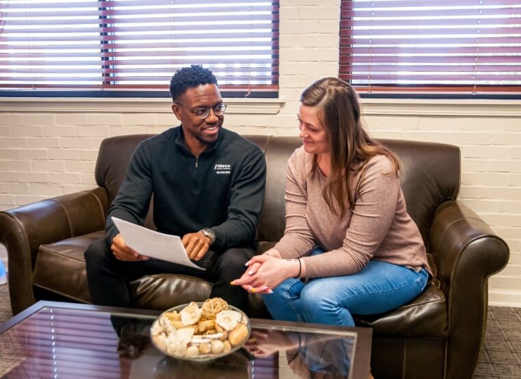 two people talking over paperwork on couch