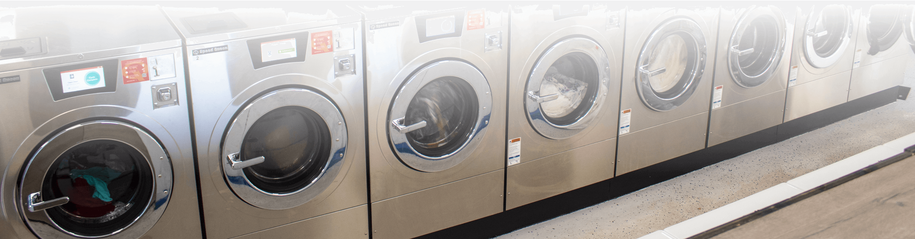 row of Speed Queen washing machines in laundromat